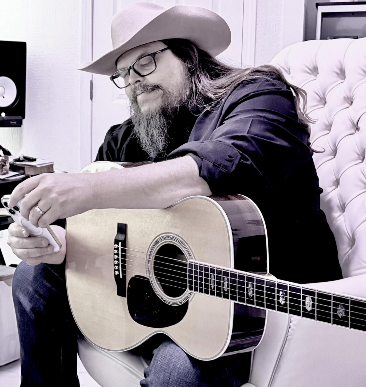 Justin Reed seated with a guitar in his studio
